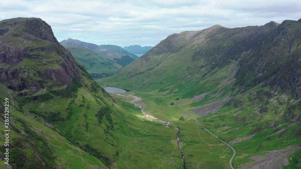 Aerial view of picturesque landscape of Glen Coe, scenic lush green valley surrounded by rocky hills of Highlands of Scotland - panorama of Scotland from above, United Kingdom, Great Britain, Europe Aerial view of picturesque landscape of Glen Coe, scenic lush green valley surrounded by rocky hills of Highlands of Scotland - panorama of Scotland from above, United Kingdom, Great Britain, Europe