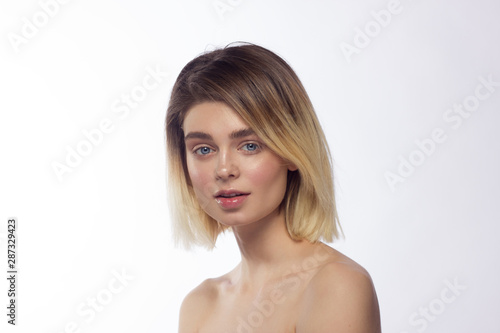 Close-up beautiful young woman face with clean perfect skin and hair. Portrait of beauty model with natural nude make up and hand near lips. Spa, skincare and wellness. Isolated on white background