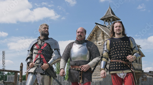 Medieval knights going on camera against wooden fortress background