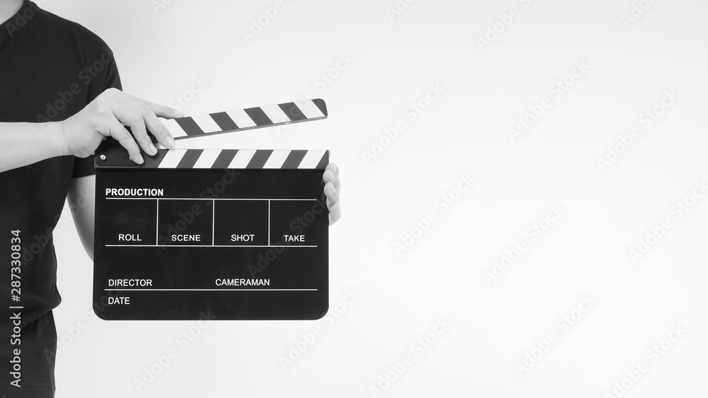 A man is standing with hands is holding black Clapperboard or movie slate. it use in video production ,film, cinema industry.It is white background.