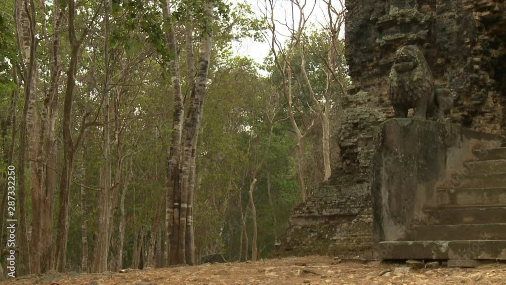 A daylight closeup shot of the surrounding forest area of the Khmer ruins of Sambor Prei Kuk partially showing one of the two carved stone lion guards and the steps going up to the entrance.. A daylight closeup shot of the surrounding forest area of the Khmer ruins of Sambor Prei Kuk partially showing one of the two carved stone lion guards and the steps going up to the entrance..