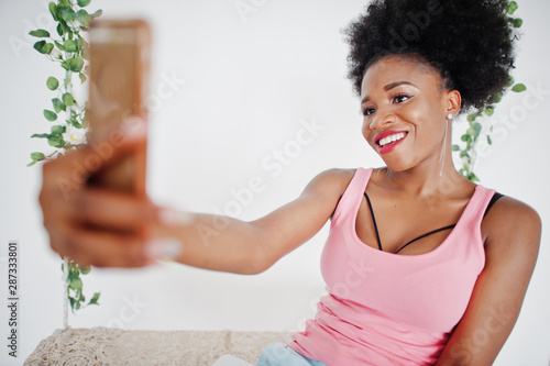Young african american woman in pink singlet making selfie on mobile phone.