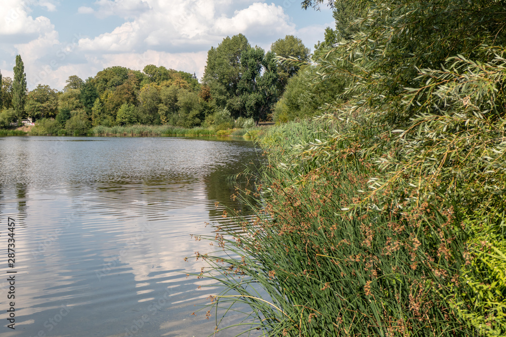 View of the popular lake Auensee in the north of Leipzig with old bridge and miniature railway View of the popular lake Auensee in the north of Leipzig with old bridge and miniature railway