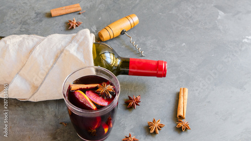 Mulled wine drink, red wine bottle and different  spices on grey concrete background. Perfect winter beverage for cold days. Top view