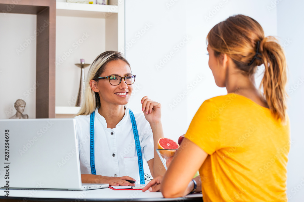 Female nutritionist giving consultation to patient. Making diet plan. Young woman visiting nutritionist in weight loss clinic Female nutritionist giving consultation to patient. Making diet plan. Young woman visiting nutritionist in weight loss clinic