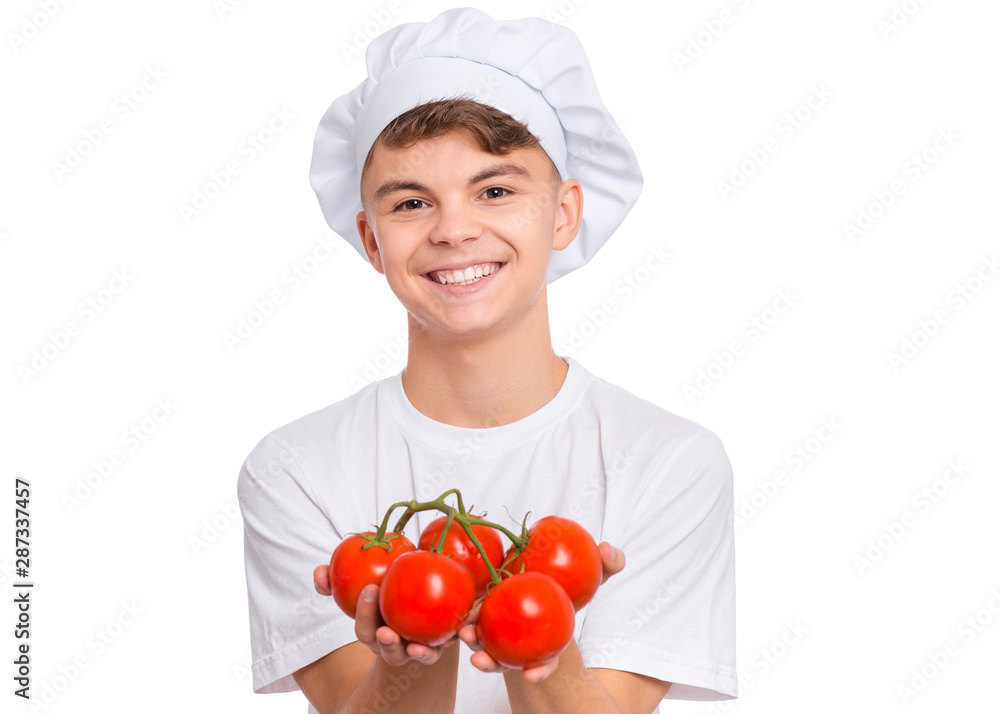 Happy teen boy in chef hat holding fresh red tomatoes branch, isolated on white background. Portrait of cute smiling child shows delicious raw vegetables in hands. Organic natural healthy food produce Happy teen boy in chef hat holding fresh red tomatoes branch, isolated on white background. Portrait of cute smiling child shows delicious raw vegetables in hands. Organic natural healthy food produce