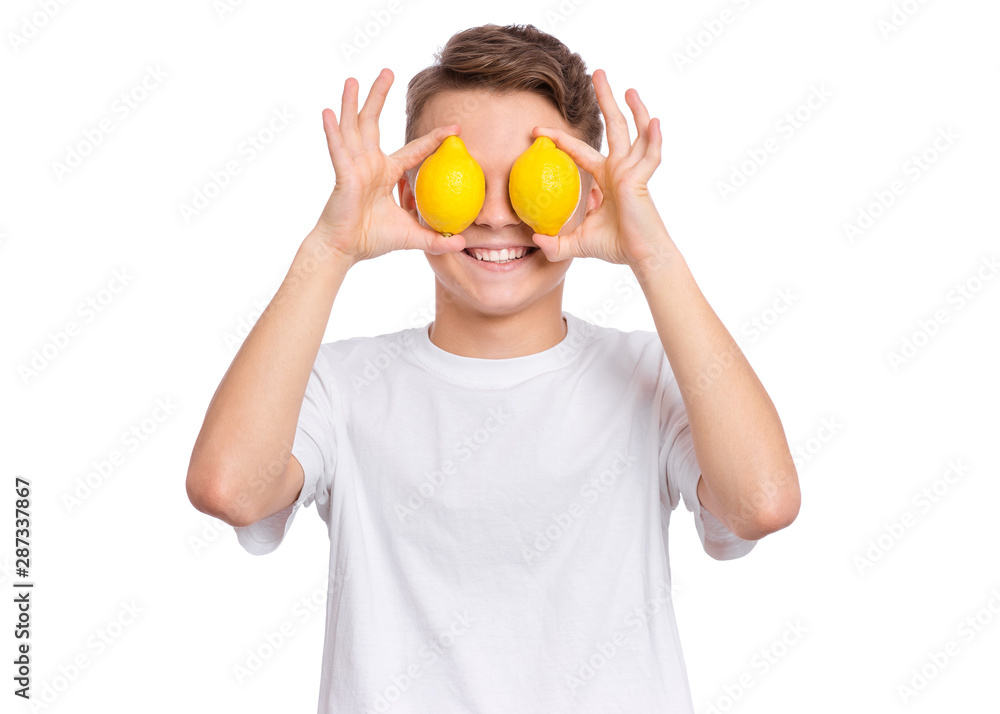 Smiling handsome young teen boy holding yellow lemons over eyes, isolated on white background. Portrait of cute happy child shows delicious vegetables in hands. Organic natural healthy food produce. Smiling handsome young teen boy holding yellow lemons over eyes, isolated on white background. Portrait of cute happy child shows delicious vegetables in hands. Organic natural healthy food produce.