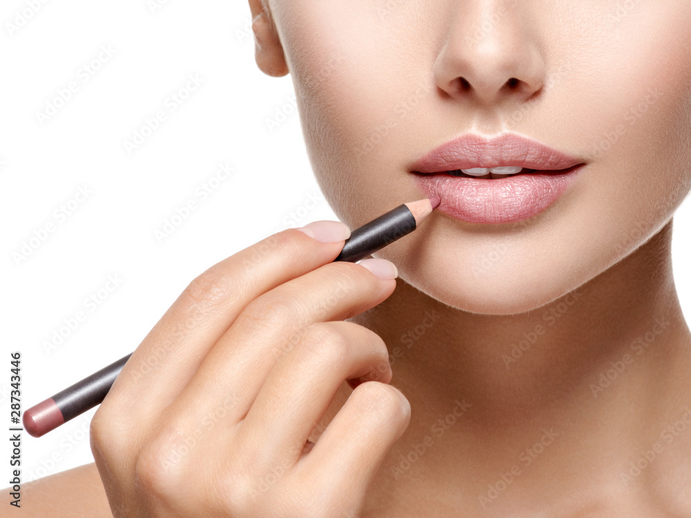 Beautiful woman applying lipstick with cosmetic pencil