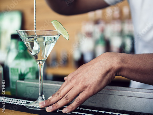 Photos Male bartender stirring cocktail in martini glass