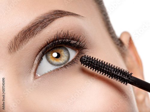 women eye with long black eyelashes and makeup brush