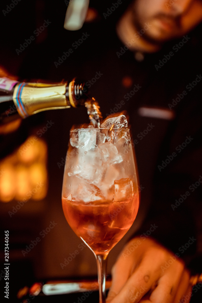 Fototapeta premium female bartender preparing aperol cocktail in a cocktail bar