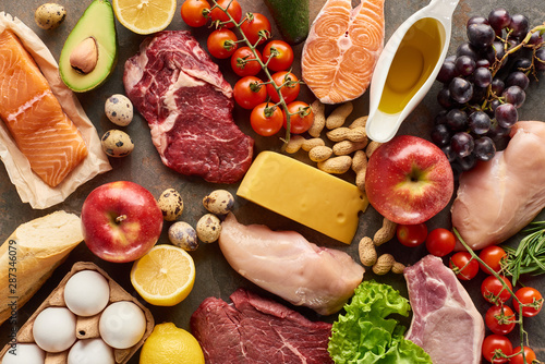 Top view of assorted meat, poultry, fish, eggs, fruits, vegetables, cheese, olive oil and baguette