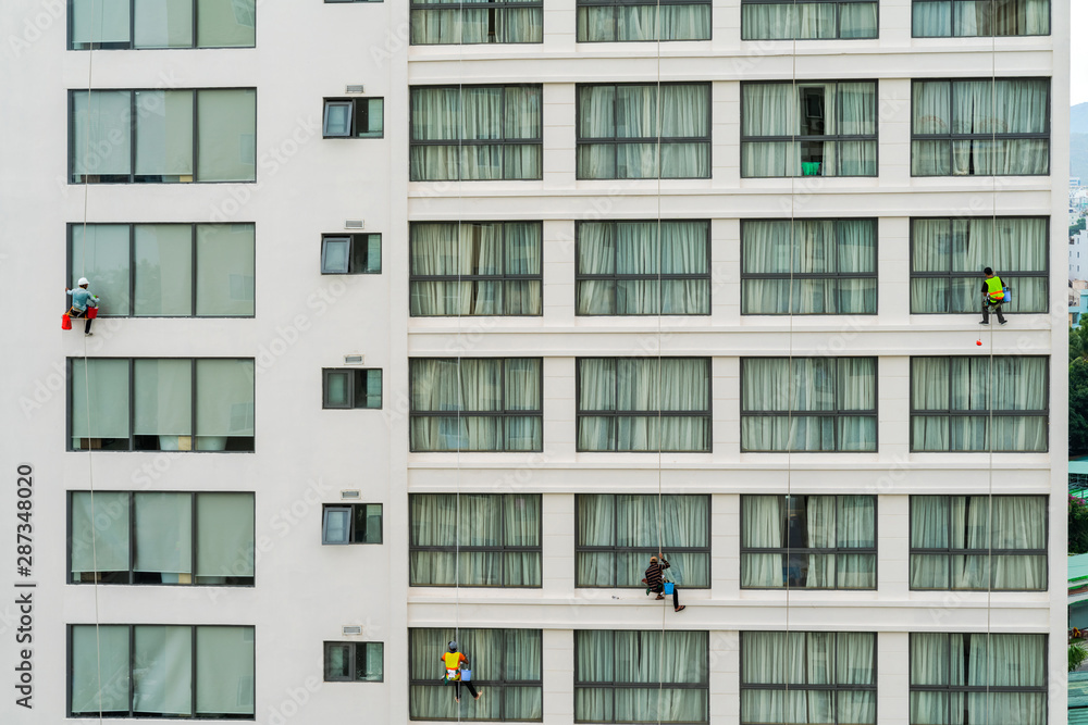 Asian industrial worker cleaning windows of a modern building. Asian industrial worker cleaning windows of a modern building.