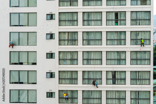 Asian industrial worker cleaning windows of a modern building. photo