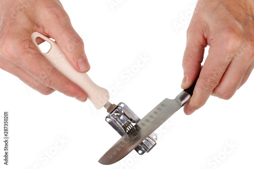 Elderly senior man sharpening a kitchen knife on a disk sharpener isolated macro