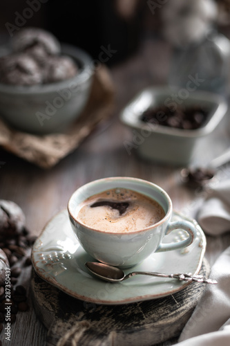 A cup of coffee with coffee beans and chocolate chip cookie on a beautiful brown background.