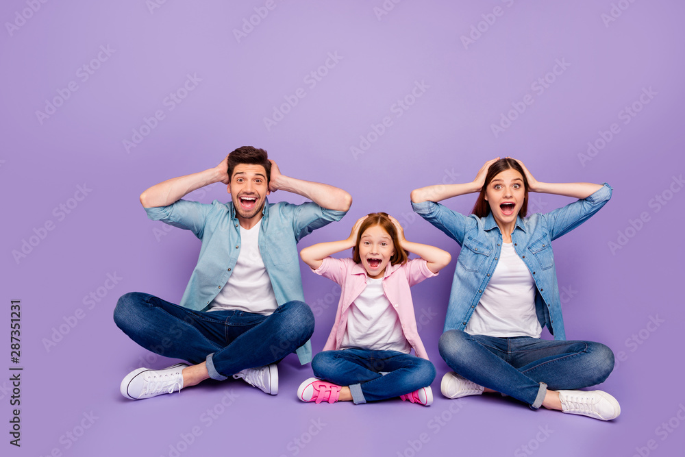 Foster family of three members sit floor holding head won lottery wear casual clothes isolated purple background Foster family of three members sit floor holding head won lottery wear casual clothes isolated purple background