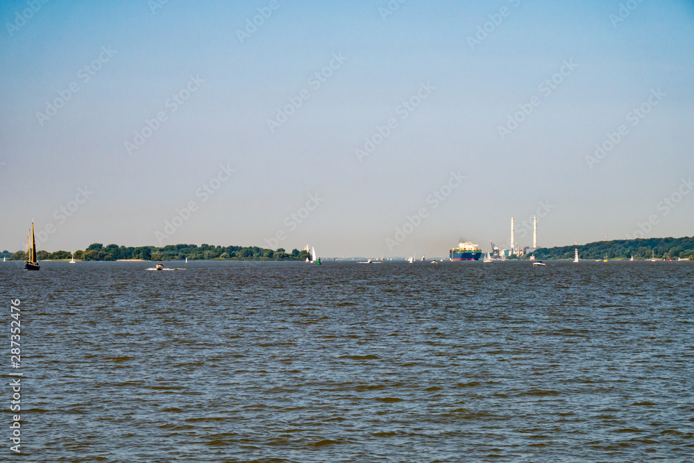 Intense ship traffic on Elbe River at sunny Sunday in late August.