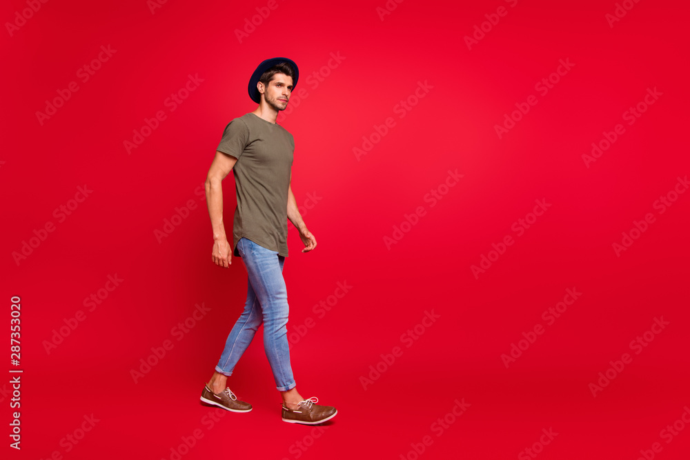 Full size photo of amazing guy walking park wear casual outfit isolated on red background Full size photo of amazing guy walking park wear casual outfit isolated on red background