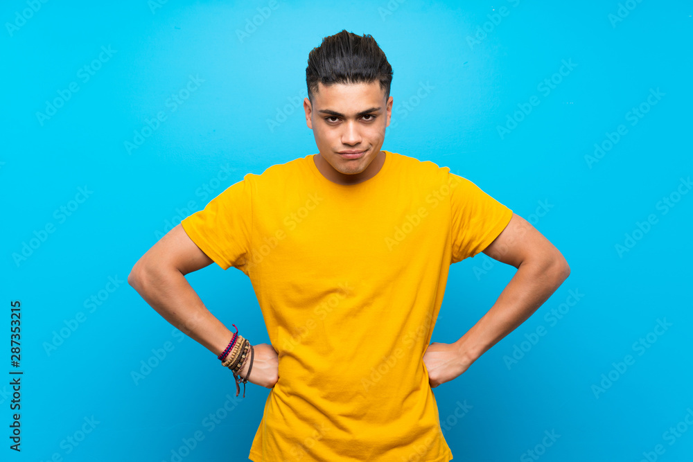Young man with yellow shirt over isolated blue background angry Young man with yellow shirt over isolated blue background angry