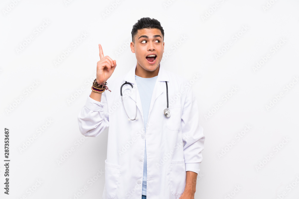 Young doctor man over isolated white wall intending to realizes the solution while lifting a finger up Young doctor man over isolated white wall intending to realizes the solution while lifting a finger up