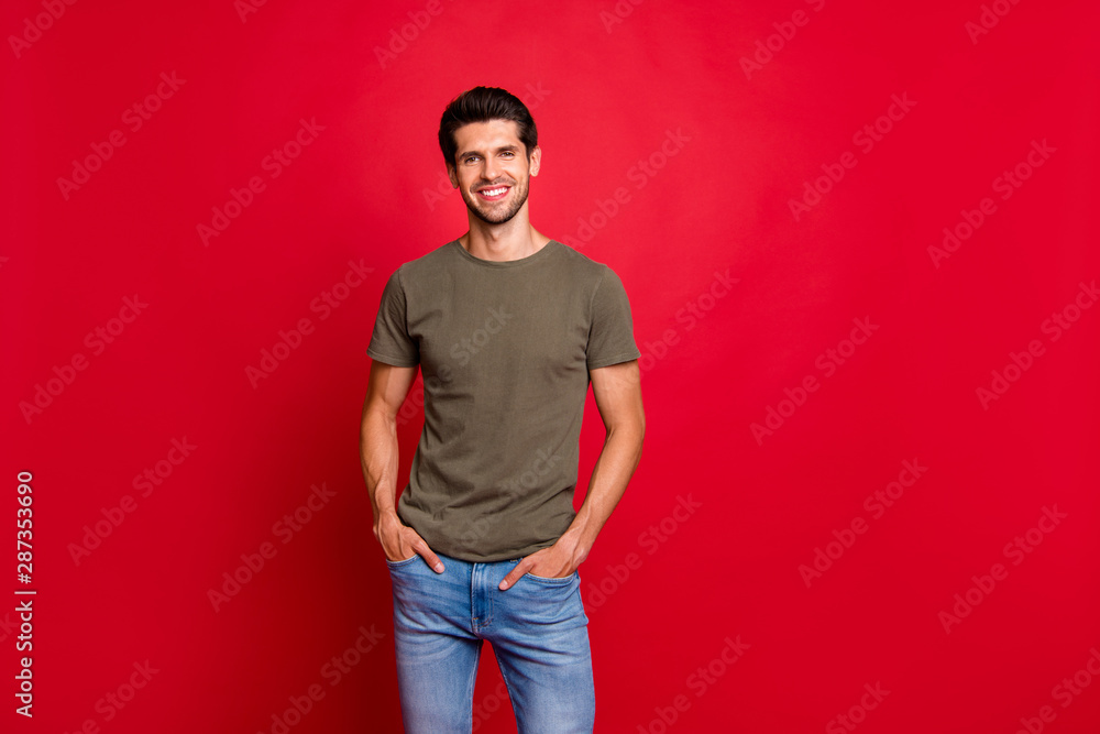 Photo of amazing guy hold hands pockets wear casual grey t-shirt isolated on red background