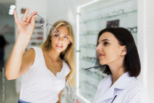 Woman checking eyeglasses frame in shop