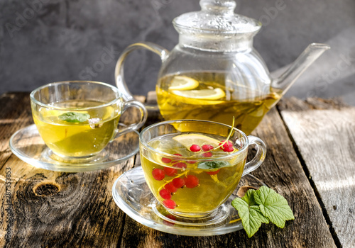  Green herbal tea with a berries in glass cup on wooden table background