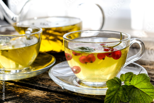 Green herbal tea with a berries in glass cup on wooden table background