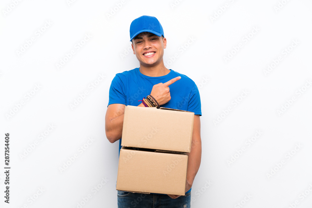 Delivery man over isolated white wall pointing to the side to present a product Delivery man over isolated white wall pointing to the side to present a product