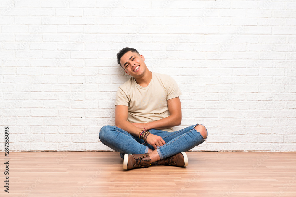 Young man sitting on the floor laughing Young man sitting on the floor laughing