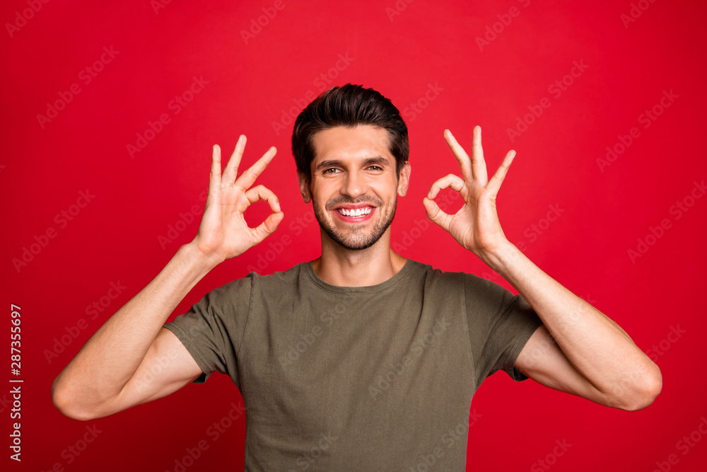 Photo of amazing guy showing okey symbol enjoy new product wear grey t-shirt isolated on red background Photo of amazing guy showing okey symbol enjoy new product wear grey t-shirt isolated on red background