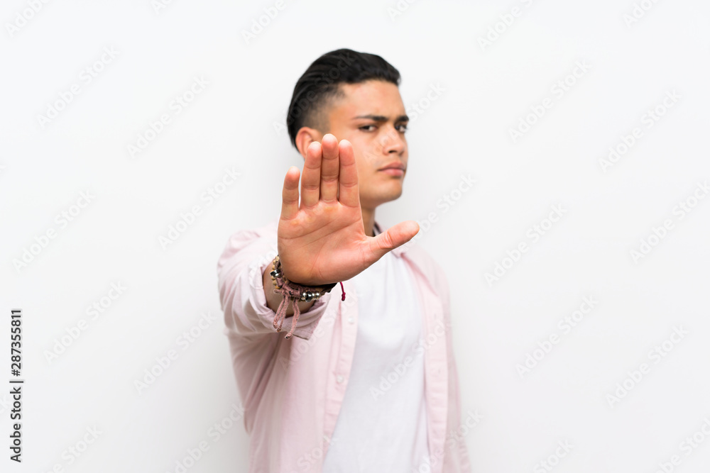 Young man over isolated white wall making stop gesture with her hand Young man over isolated white wall making stop gesture with her hand