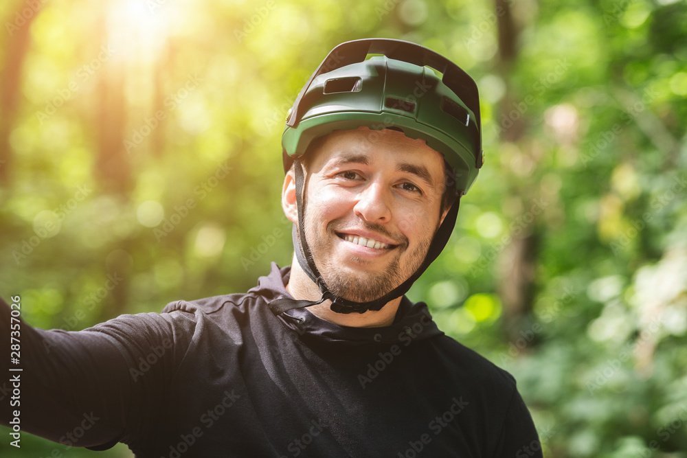 Happy smiling cyclist man taking selfie in green forest Happy smiling cyclist man taking selfie in green forest
