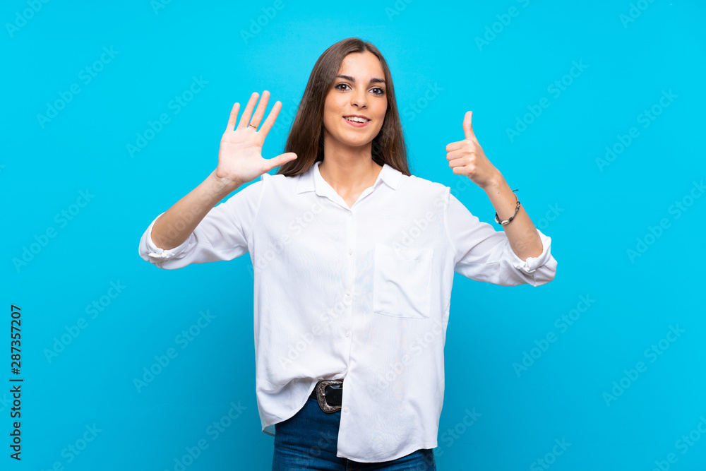 Young woman over isolated blue background counting six with fingers Young woman over isolated blue background counting six with fingers