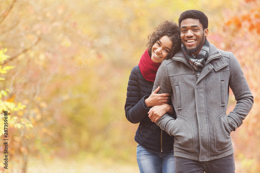 Romantic walk. Afro couple walking through autumn park Romantic walk. Afro couple walking through autumn park