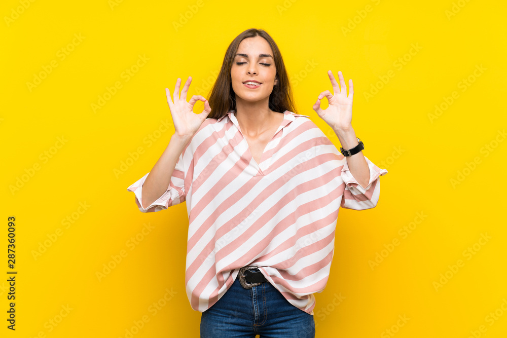 Young woman over isolated yellow background in zen pose Young woman over isolated yellow background in zen pose