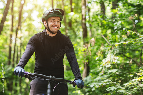 Joyful male bicyclist cycling in mountain forest photo