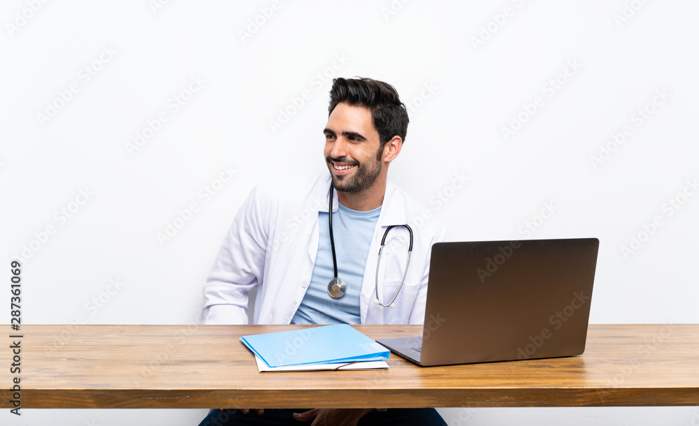Young doctor man with his laptop over isolated wall Young doctor man with his laptop over isolated wall