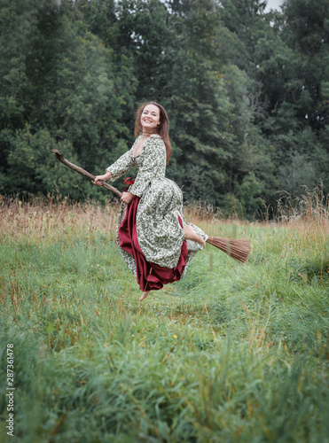 Beautiful woman in medieval dress flying on the broom