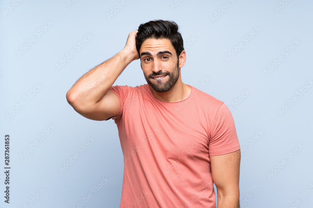 Handsome young man in pink shirt over isolated blue background with an expression of frustration and not understanding Handsome young man in pink shirt over isolated blue background with an expression of frustration and not understanding
