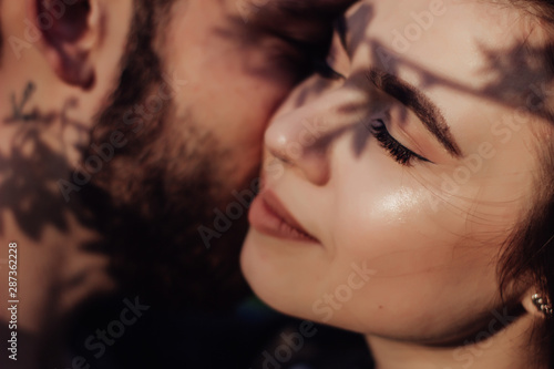 Head shot of young affectionate romantic couple in love. Close up portrait of attractive brunette girl and guy with eyes closed, close to each other. Concept of first kiss, tenderness and amorousness.