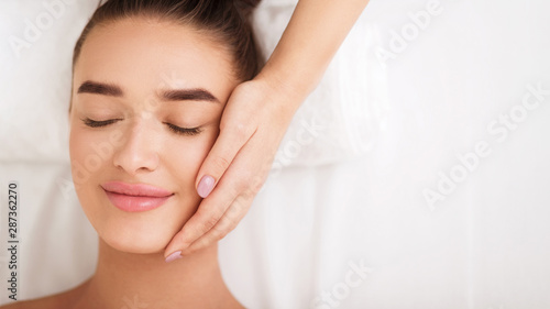 Woman getting facial spa treatment, enjoying face massage