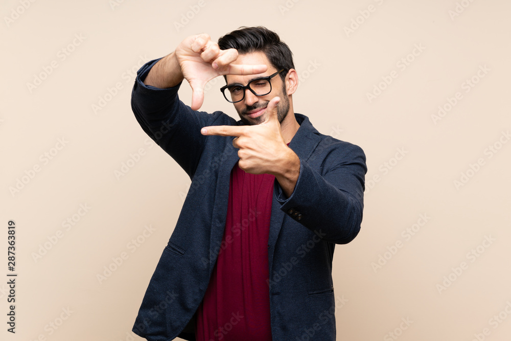 Handsome young man over isolated background focusing face. Framing symbol