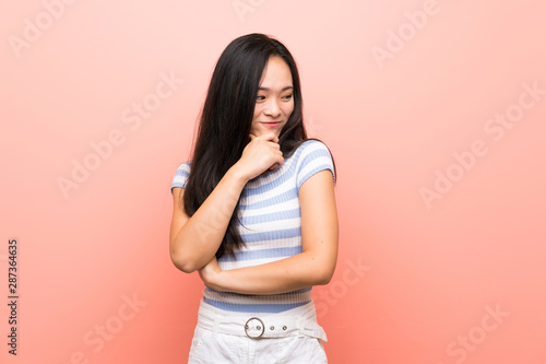 Teenager asian girl over isolated pink background looking to the side