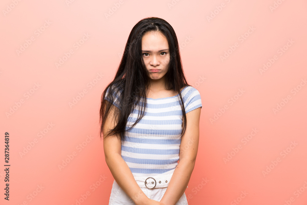 Obraz premium Teenager asian girl over isolated pink background with sad and depressed expression