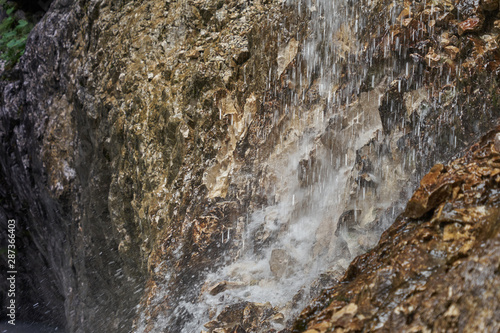 Intentionally Blurred water drops splashing between rocks to a stream