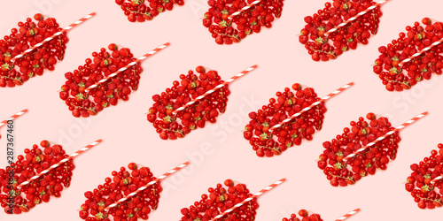 Summer fruit concept pattern. Red ripe berries in the shape of a glass with fruit juice and a straw