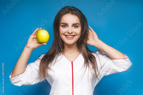 Pretty girl on blue background with apple, healthy life concept. © Тарас Нагирняк