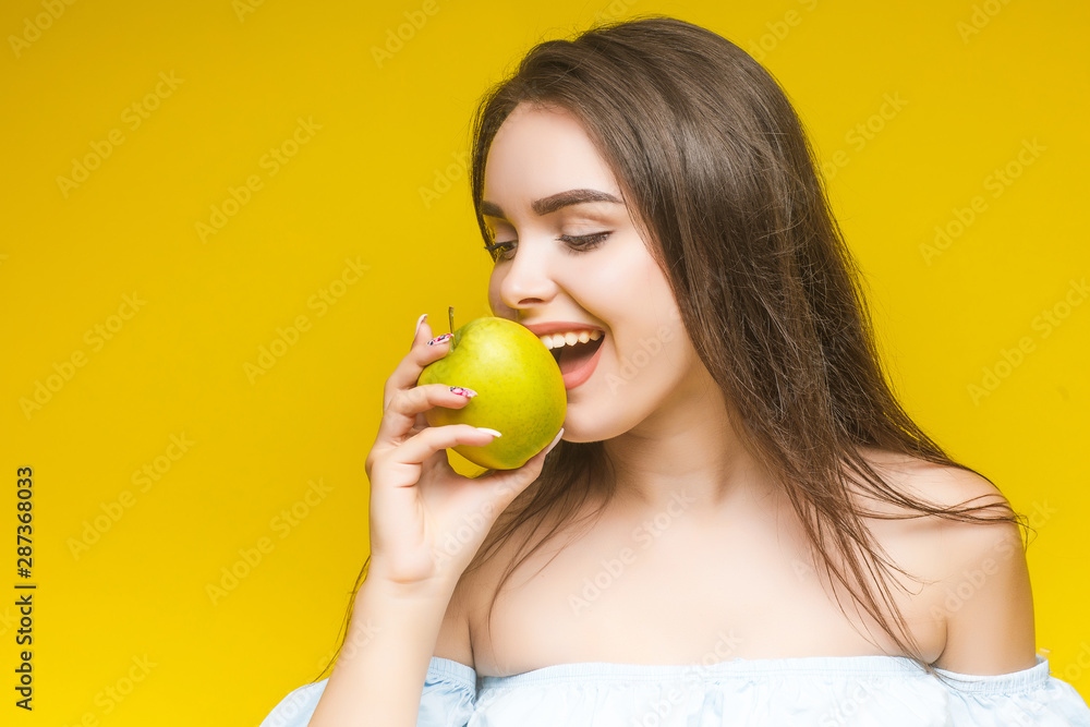 Young cheerful woman with apple, isolated over yellow background. Young cheerful woman with apple, isolated over yellow background.